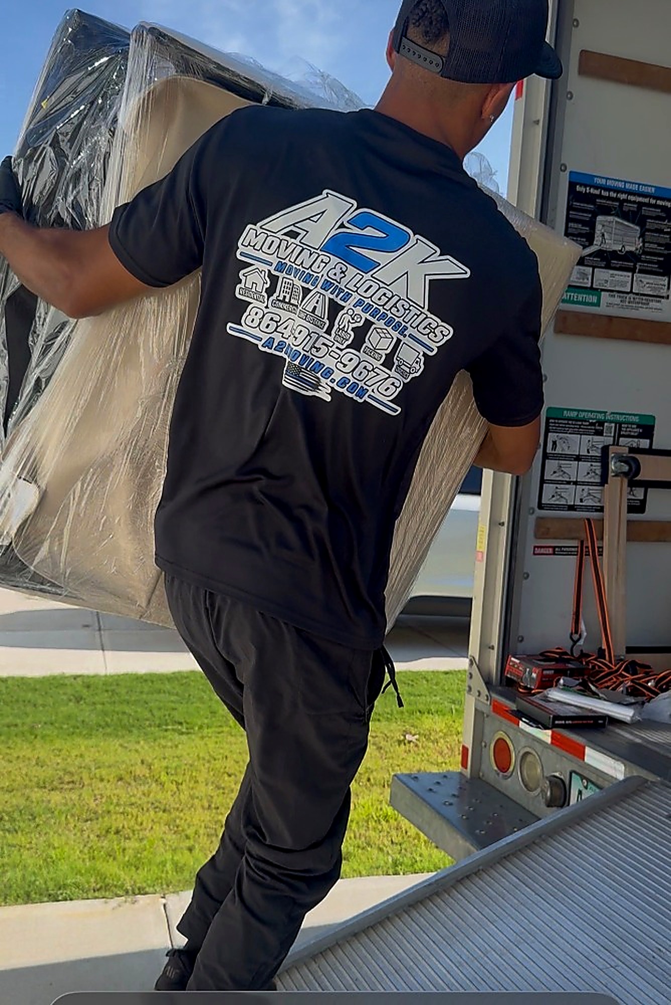 A2K mover carrying a wrapped mattress up a truck ramp